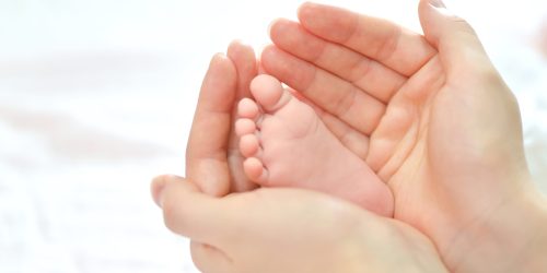 Baby feet in mother hands. Mom and her Child. Happy Family concept. Beautiful conceptual image of Maternity